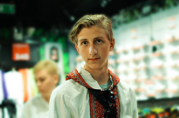 Portret van een blonde man in Oekraïens geborduurd shirt die in de camera kijkt  - Foto, afbeelding