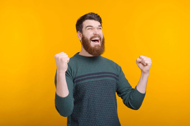 Oh yeah, I got it. Happy bearded guy is making the winner gesture on yellow background - Photo, image