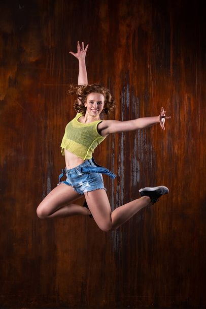 Beautiful girl in casual clothes dancing indoor at loft room with rusty background - Photo, image