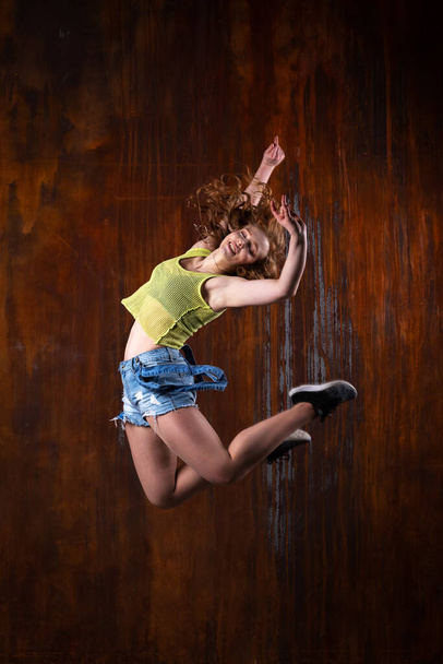 Beautiful girl in casual clothes dancing indoor at loft room with rusty background - Fotoğraf, Görsel