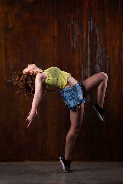 Beautiful girl in casual clothes dancing indoor at loft room with rusty background - Foto, Imagen
