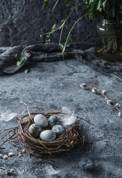 Kuş yuvasında mermer Paskalya yumurtaları kuş tüyleri ve bahar laleleri ile mavi arka planda ışık. Mutlu Paskalyalar - Fotoğraf, Görsel