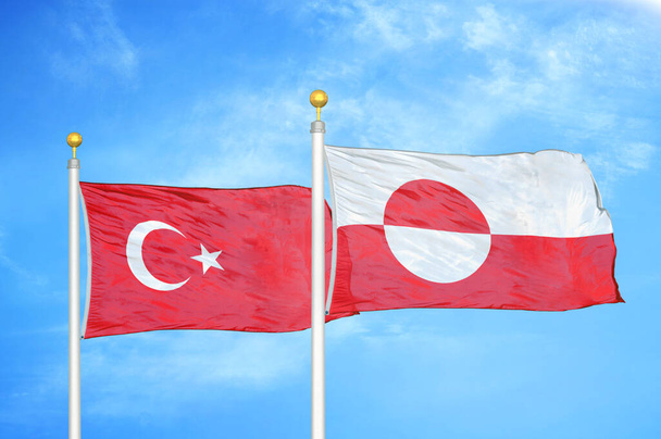 Turkije en Groenland twee vlaggen op vlaggenmasten en blauwe bewolkte lucht achtergrond - Foto, afbeelding