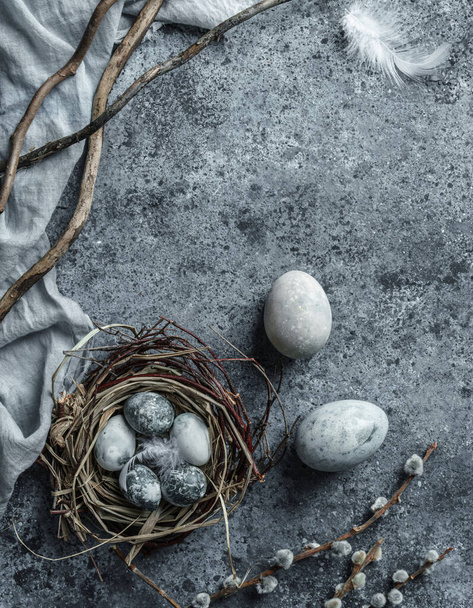 Marble Easter eggs in bird nest with feathers and spring flowers on blue background with napkin. Happy Easter holiday, top view, flat lay - Foto, Imagen