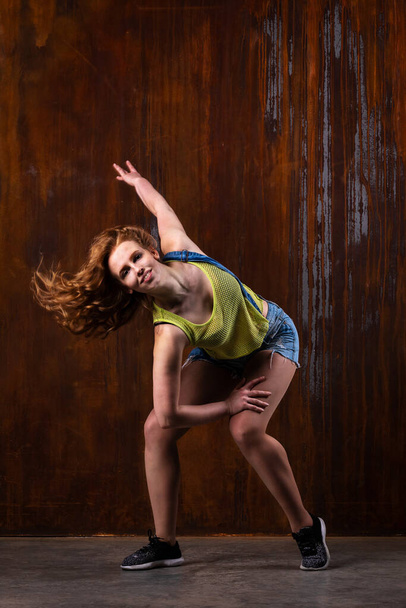 Beautiful girl in casual clothes dancing indoor at loft room with rusty background - Foto, imagen