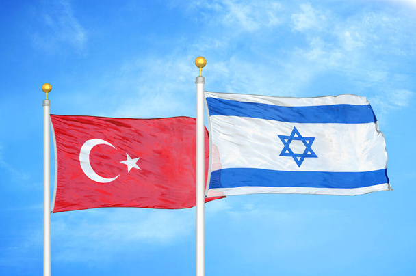 Turkije en Israël twee vlaggen op vlaggenmasten en blauwe bewolkte lucht achtergrond - Foto, afbeelding