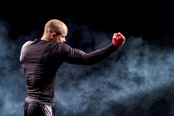 煙と黒の背景で戦うスポーツマンボクサー。ボクシングスポーツのコンセプト - 写真・画像