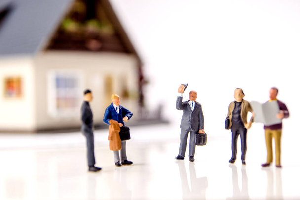 the decision about sell or buy a new residence as an investment oportunity, a team of miniature figurines deciding about a new financial possibility, sell and buy white dices - Photo, Image