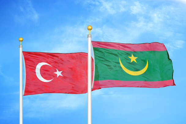 Turkije en Mauritanië twee vlaggen op vlaggenmasten en blauwe bewolkte lucht achtergrond - Foto, afbeelding