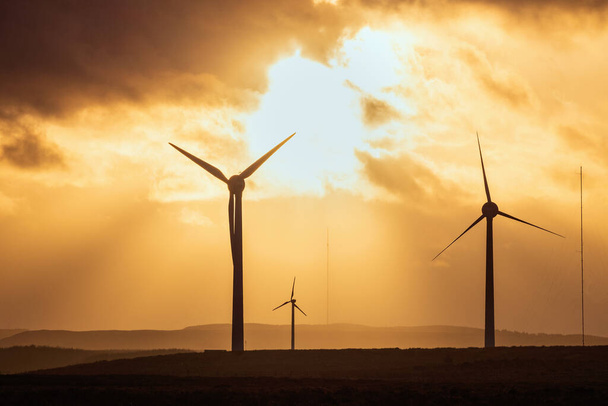劇的な空を背景に日没のフィールドで風車。西ロシア,スコットランド,イギリス - 写真・画像