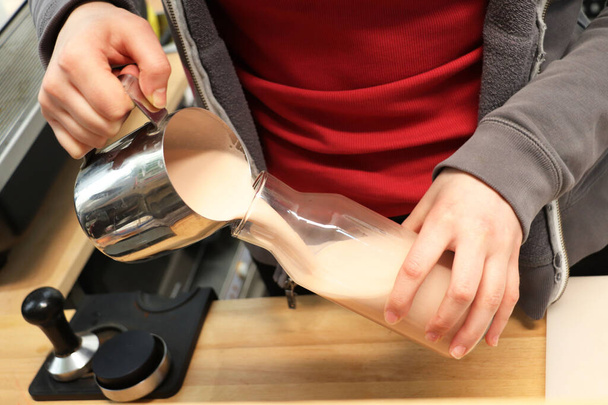 Haciendo café. Chica está batiendo la leche con una máquina de café
 - Foto, Imagen