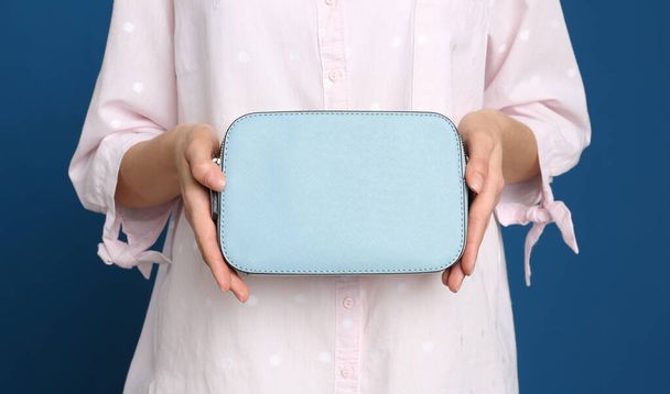 Young woman with stylish bag on blue background, closeup - Foto, afbeelding