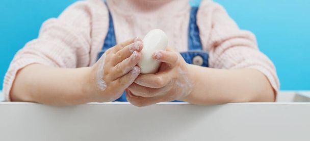Koncept hygieny rukou. Ženské ruce drží antibakteriální mýdlo s pěnou na modrém pozadí. Ruční antiseptikum během pandemie koronoviru - Fotografie, Obrázek