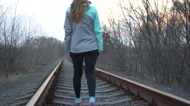 Το κορίτσι πάει σιδηροδρομικώς. Ένα μοναχικό κορίτσι πηγαίνει κατά μήκος της σιδηροδρομικής γραμμής. - Πλάνα, βίντεο