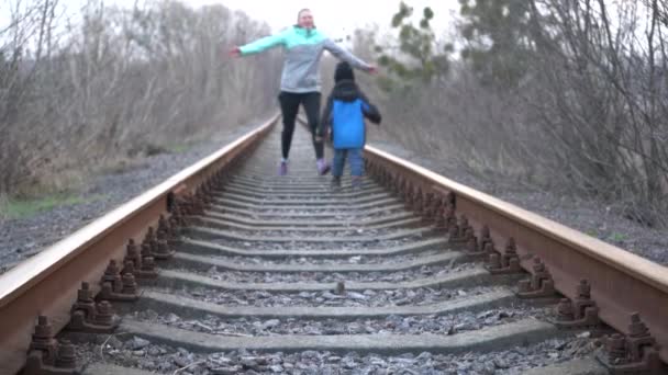 Une fille avec un adolescent et un enfant sont assis sur le chemin de fer. Les enfants jouent sur le chemin de fer
. - Séquence, vidéo
