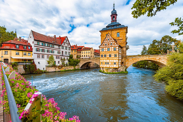 Bamberg. Rathausgebäude im Hintergrund mit blauem bewölkten Himmel. Architektur und Reisen in Europa. Fließender Fluss im Vordergrund. - Foto, Bild