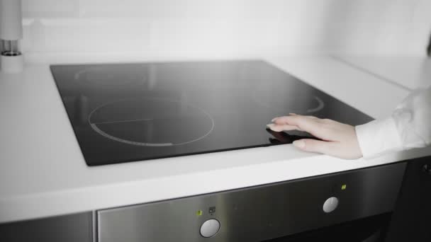 Zbliżenie kobiecej ręki włączonej kuchenkę indukcyjną - Materiał filmowy, wideo