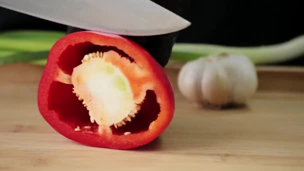 A cook cuts a red pepper with a sharp knife on a cutting board - Footage, Video