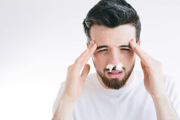 Portrait of young sick man with headache holding forehead in pain. Nose sneezing. Coronavirus. Brunette bearded man isolated over background. - Fotografie, Obrázek