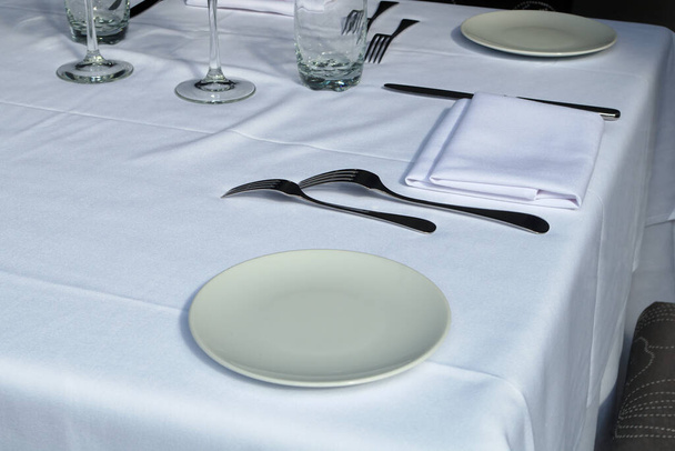 ravintola pöytä asettamalla valkoinen pöytäliina lautasliinat ja lasi
 - Valokuva, kuva
