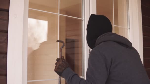 Zloděj s páčidlem se snaží dostat do domu u zadních dveří. Zloděj se dívá zavřenými dveřmi do domu - Záběry, video