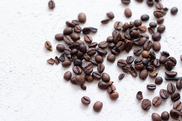 Kaffeebohnen sind auf einem hellen Hintergrund verstreut. Frische Kaffeebohnen. Konzept der Werbung für Kaffee, Kaffeebohnen, Cafés. Raum für Text - Foto, Bild