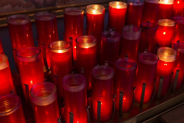 Rode gebedskaarsen aangestoken in rijen katholieke kerk - Foto, afbeelding
