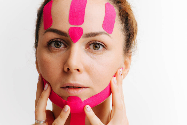 primer plano de una cara de las niñas con cinta antiarrugas rosa cosmetológica
 - Foto, imagen
