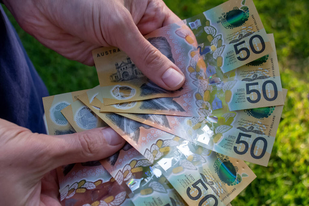 Руки, що тримають австралійські долари 50 банкнот для здійснення платежу
 - Фото, зображення