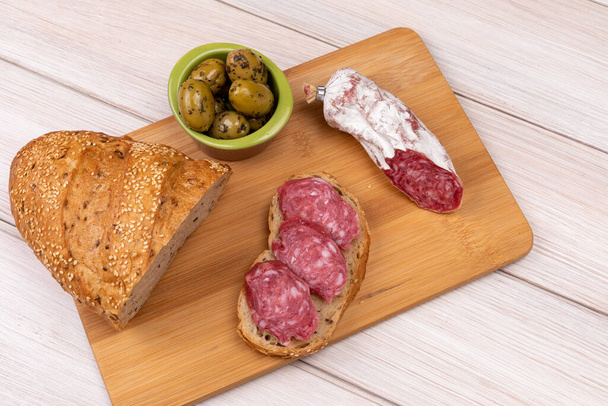 Sandwich de saucisses séchées, d'olives et un pain de grains entiers sur une planche de bois. Le concept de la nourriture abordable simple. Vue du haut
 - Photo, image