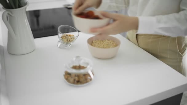Ceramic bowl of oatmeal porridge with banana, date, dried apricots, nuts. Healthy breakfast and diet food. - Záběry, video