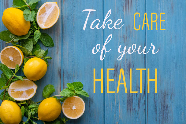 Take care of your health. Greeting card with the inscription, lemons, mint on a blue wooden background. Vitamin C. The fight against viruses and colds - Fotó, kép