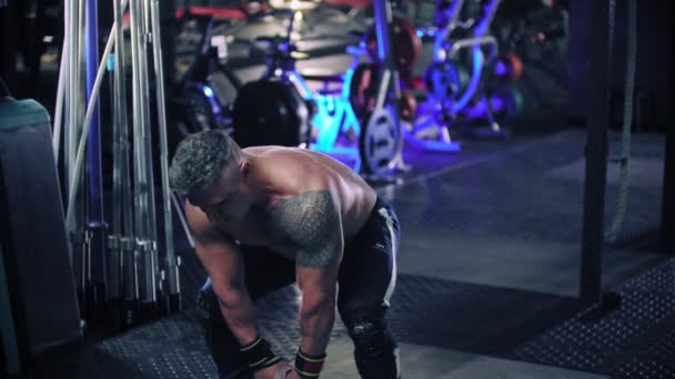 A tough man with gray hair bodybuilder pulls a kettlebell in the gym - Záběry, video