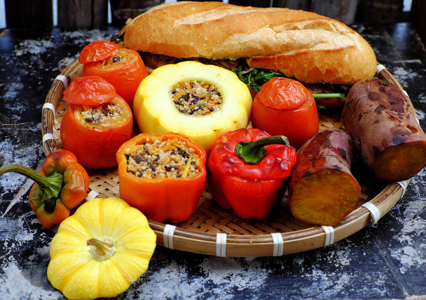 Βιετναμέζικο φαγητό για χορτοφάγους, δίσκος χορτοφαγικό γεύμα με ψητά λαχανικά από γεμιστή κόκκινη ντομάτα, πιπεριές, κίτρινη κολοκύθα με φασόλια σόγιας και μανιτάρια και βραστή γλυκοπατάτα και ψωμί - Φωτογραφία, εικόνα