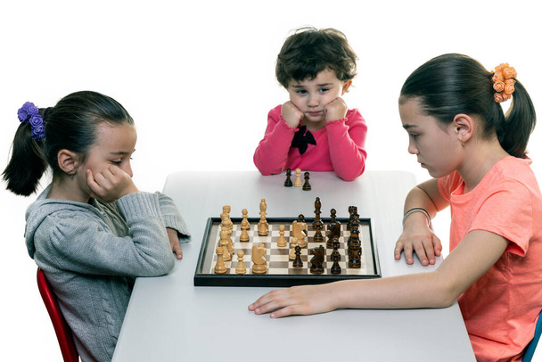 Sorelle che giocano a scacchi insieme isolate sul bianco. Concetto di concentrazione bambini
. - Foto, immagini