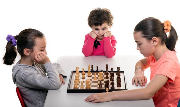 Sisaret pelaavat shakkia yhdessä eristyksissä valkoisella. Lasten keskittymiskäsite
. - Valokuva, kuva