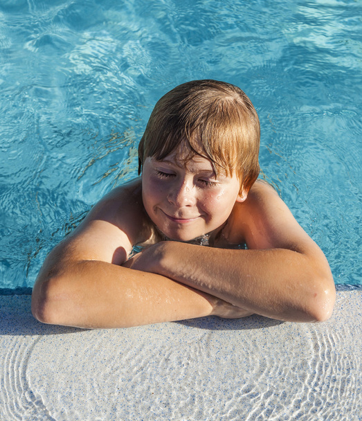 Criança descansa em seu cotovelo na borda da piscina
 - Foto, Imagem