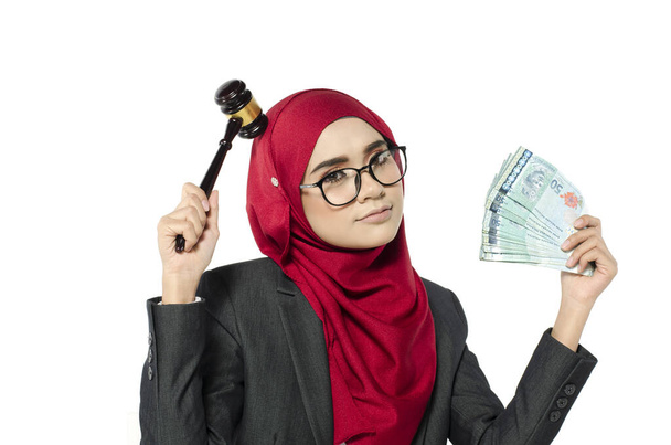 Концепция аукциона или коррупция судебной системы, портрет молодой женщины в хиджабе, держащей деньги и судья молоток
. - Фото, изображение