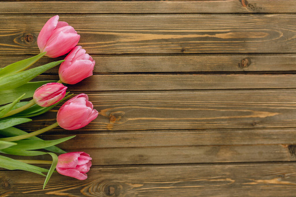 Bouquet of pink tulips on brown wooden background. Top view, copy space - Foto, Bild