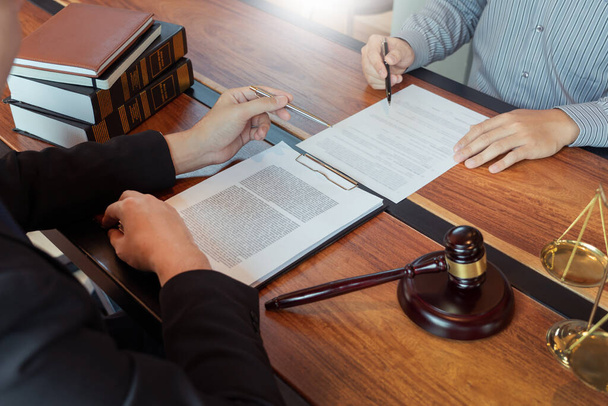 依頼人と仕事をする弁護士は、法廷での法規制に関する真鍮のスケールで契約書を議論し、顧客を助けるためにコンサルティング - 写真・画像