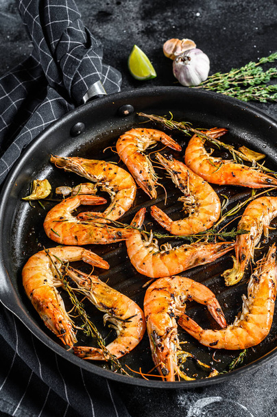 Grilled giant prawns, shrimps with garlic, lemon, spices in pan. Black background. Top view. - Photo, Image