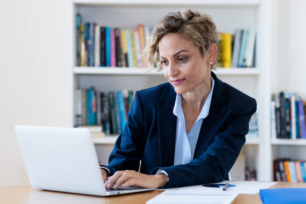 Mature adult businesswoman working at computer at home office because quarantine - Foto, Imagen