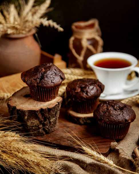 three chocolate muffins served in rustic style on wooden boards - Foto, imagen