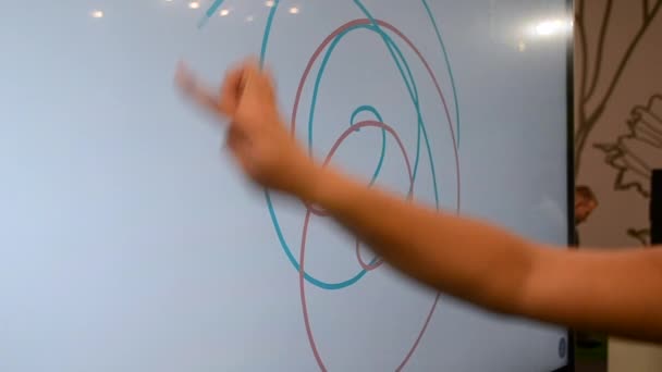 Meisje tekent met haar vinger verschillende gekleurde spiraallijnen op een grote touch - Video