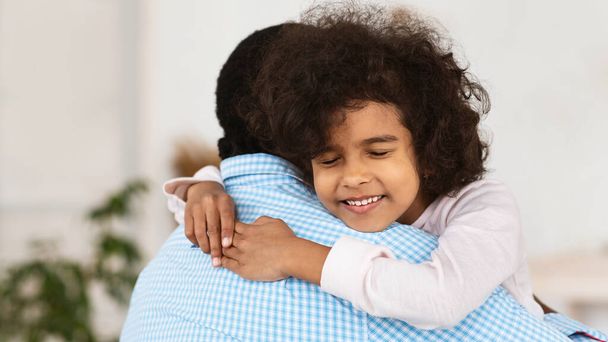 Liebenswertes afroamerikanisches Mädchen umarmt ihren Opa zu Hause - Foto, Bild