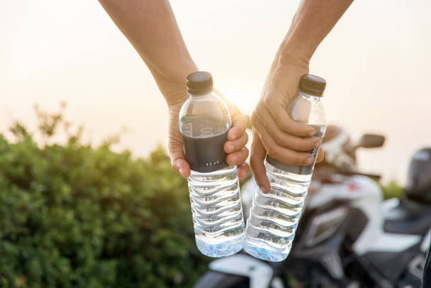 Ręczne trzymanie butelki wody z dużym tle rower, letnie wakacje na świeżym powietrzu i widok w godzinach wieczornych, Napoje, ludzie i lifestyl - Zdjęcie, obraz