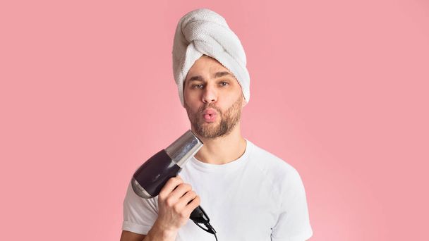 Ο άνθρωπος φυσάει στο στεγνωτήριο μαλλιών όπως στο όπλο - Φωτογραφία, εικόνα