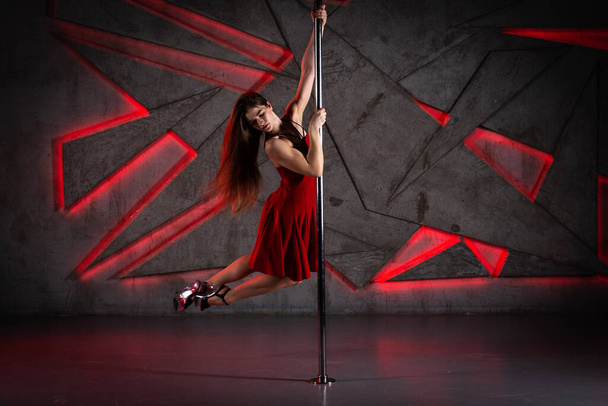 Beautiful girl dancing in red dress and high heels on pole at dance studio - Zdjęcie, obraz