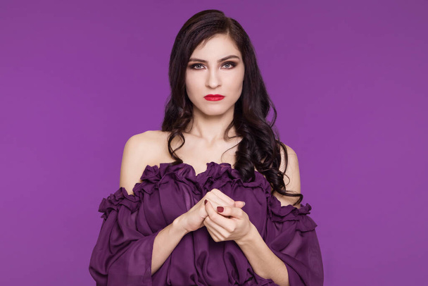 A brunette woman in an airy dress unhappy, angry, evil muse. Purple background. - Photo, Image