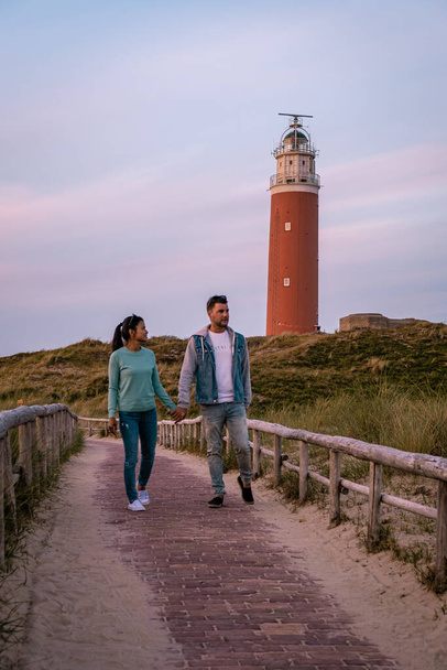 Texel latarnia morska podczas zachodu słońca Holandia Dutch Island Texel, para odwiedzić latarnię morską, mężczyźni i kobieta na wakacjach Texel - Zdjęcie, obraz